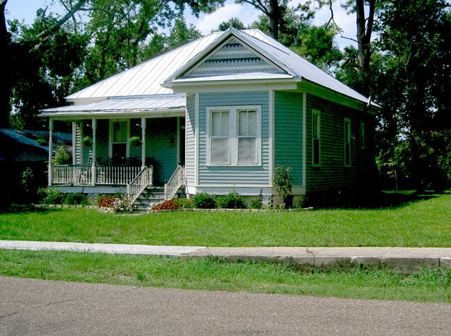 The James A. Herod House, a historic cottage with a deep front porch shaded by old trees