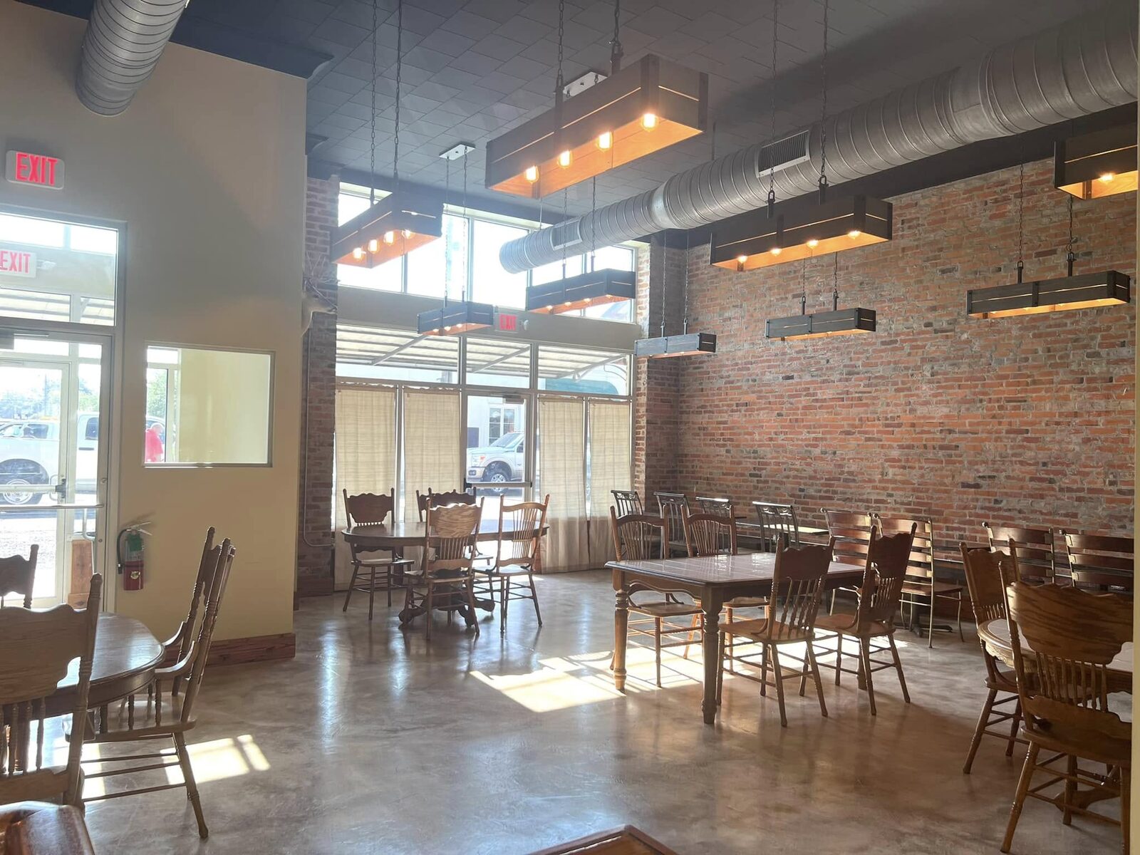 Sunlight pouring through tall windows onto exposed brick and gathered tables inside The Russo