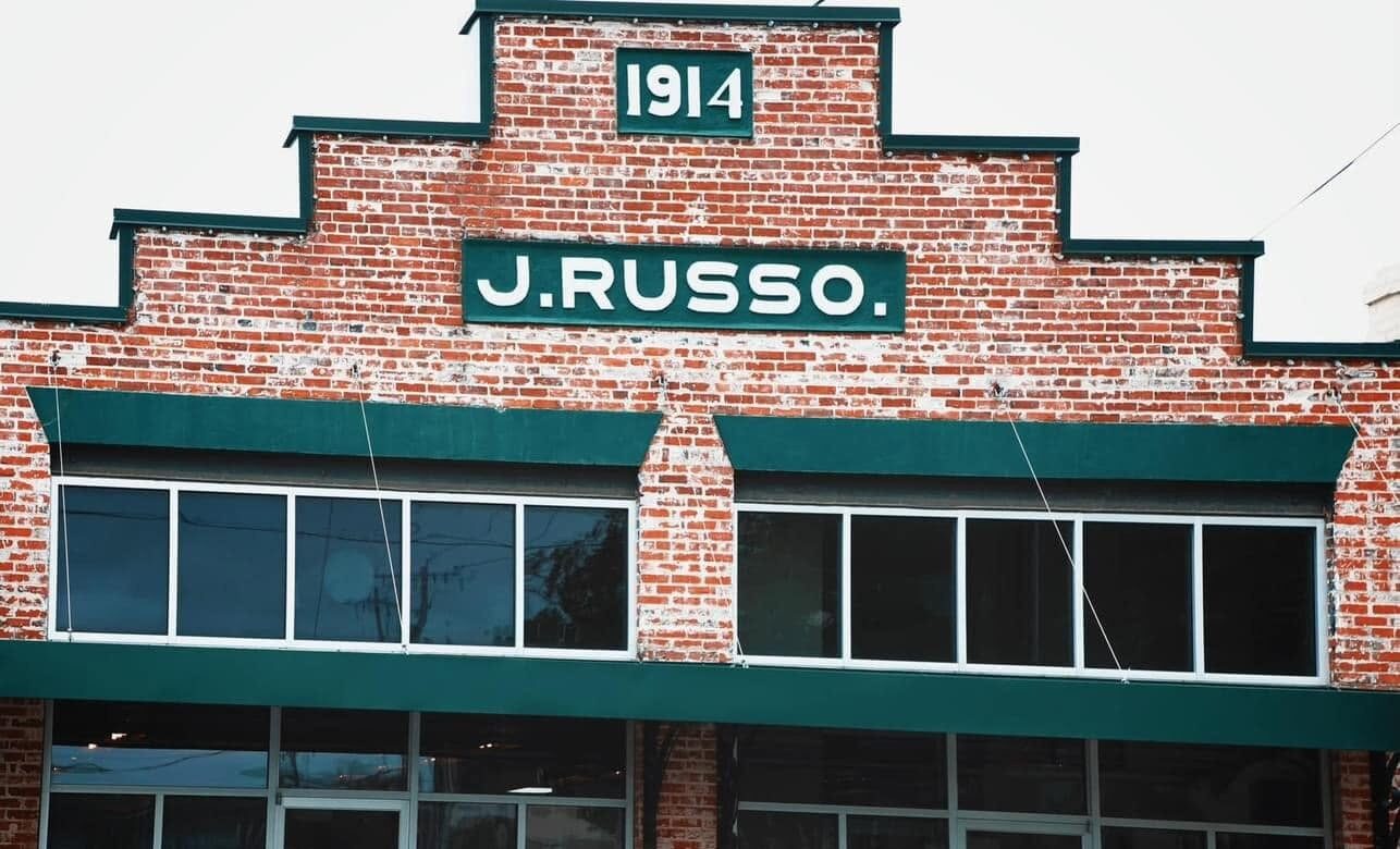 The stepped brick facade of The Russo, its green signage reading J. Russo and 1914