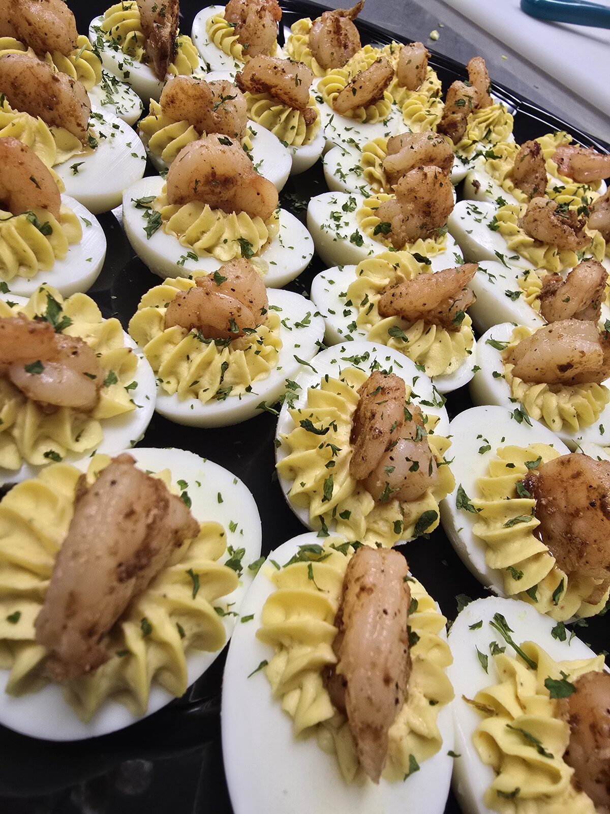 Deviled eggs piped with whipped yolk, crowned with seasoned Gulf shrimp and a scatter of fresh parsley