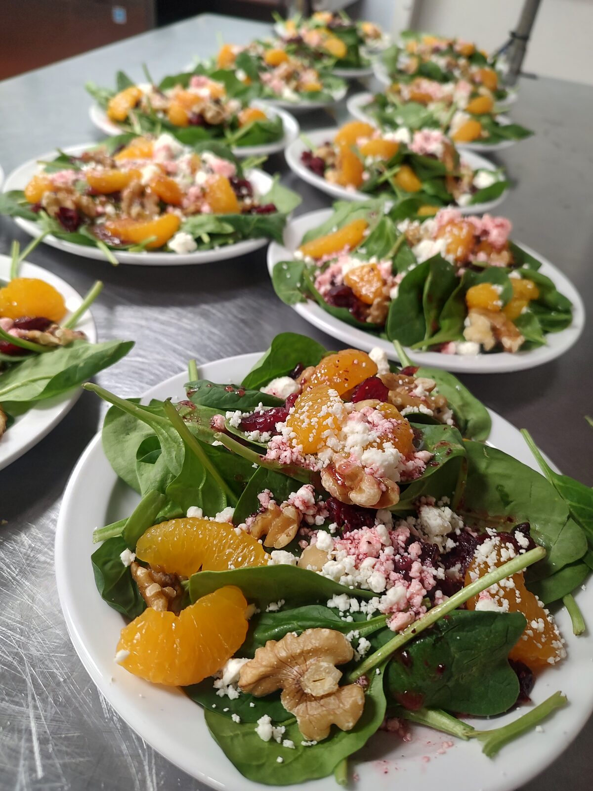 A spinach salad studded with pomegranate seeds, crumbled cheese, and candied nuts