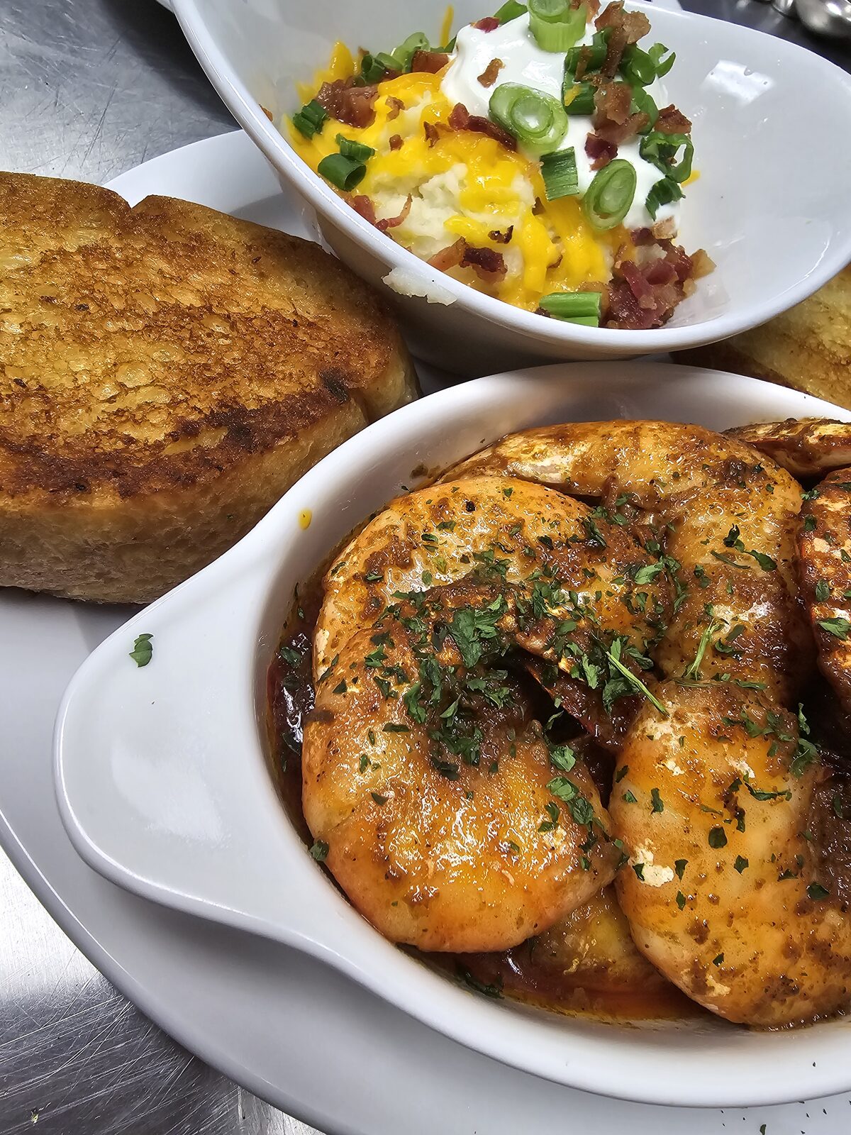 Seasoned jumbo shrimp in a buttery pan sauce, served in a crock with toasted garlic bread and loaded mashed potatoes